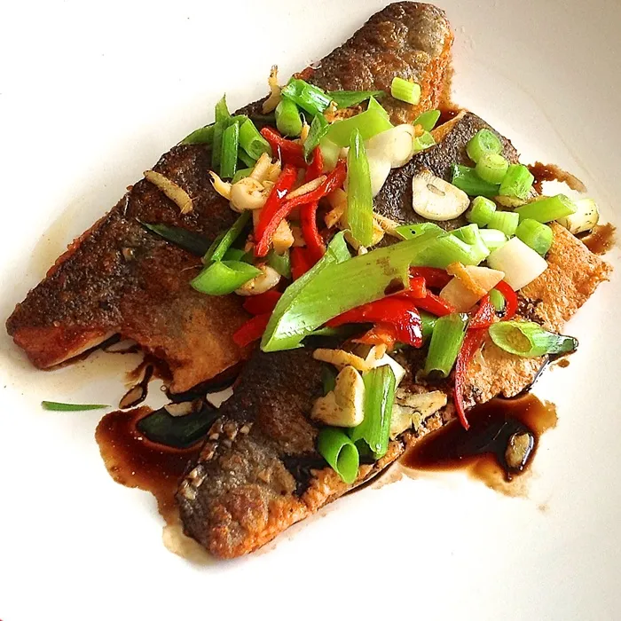 Branzino con zenzero saltato in padella, peperoncino e cipollotti